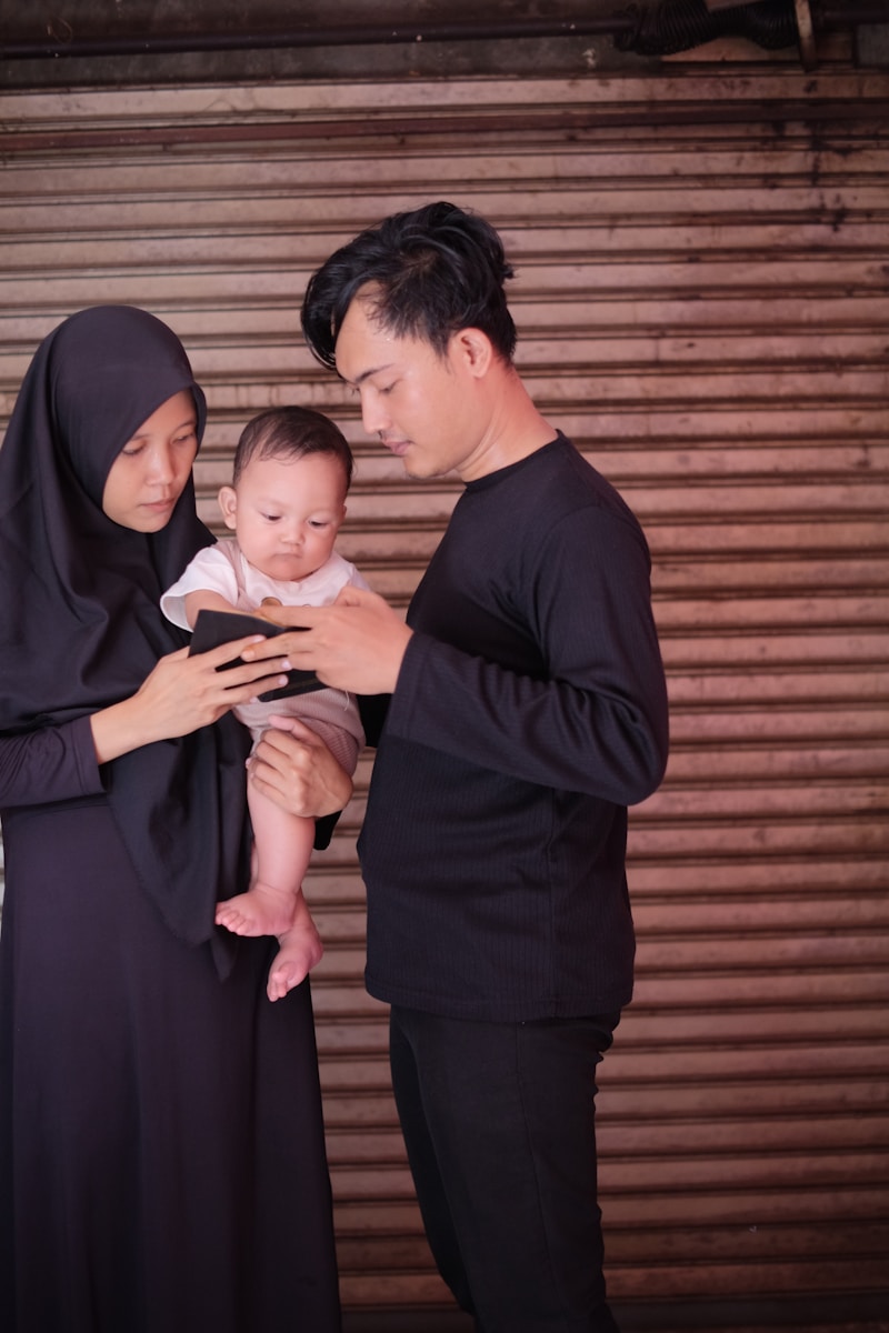 a man and woman holding a baby while looking at a cell phone