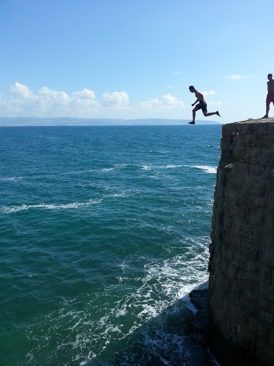 two people jumping off a cliff into the ocean