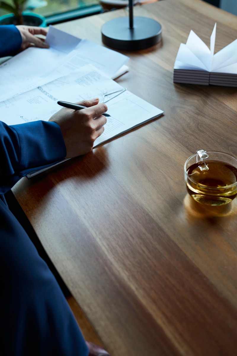 a person sitting at a table writing on a piece of paper