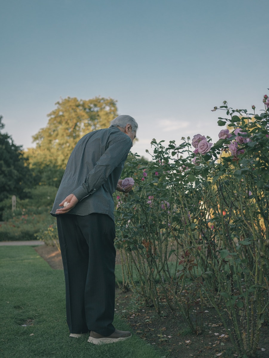 Photo by huan yu A man standing in the grass next to a bush