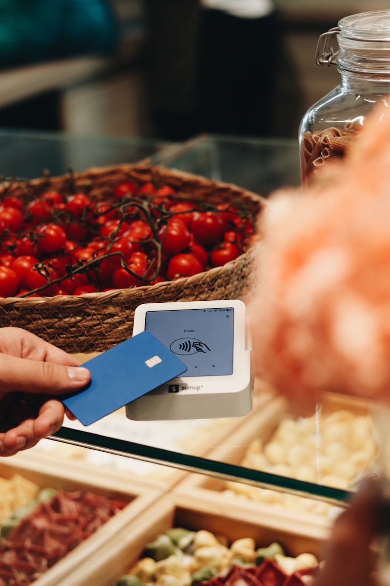 A person holding a credit card in front of a display of food