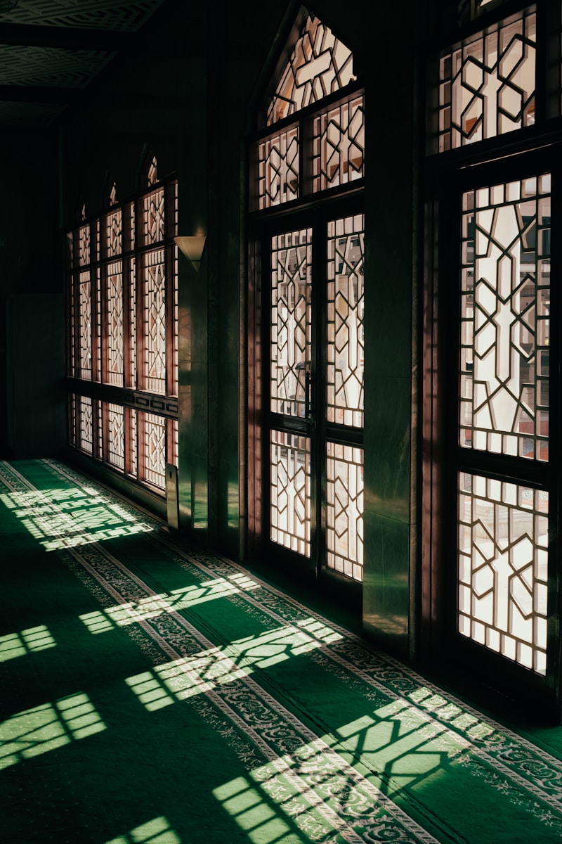 Sunlight streams through ornate windows on a green carpet.