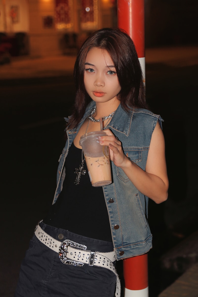 a woman standing next to a pole with a drink in her hand