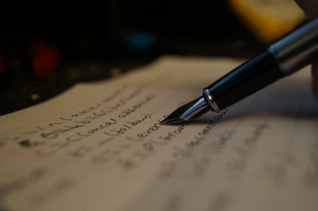 a person writing on a piece of paper with a pen