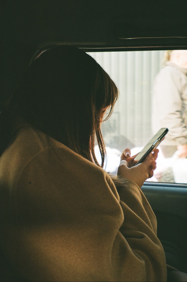 a woman sitting in a car holding a cell phone