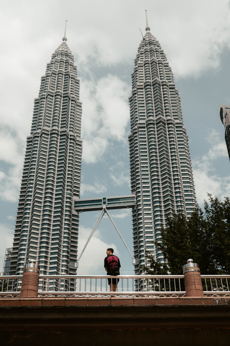 a man standing on a bridge in front of two tall buildings