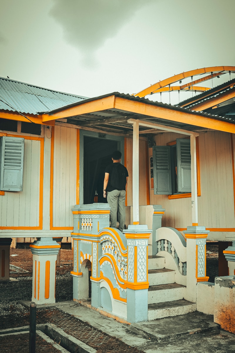 a man standing in the doorway of a yellow and white house