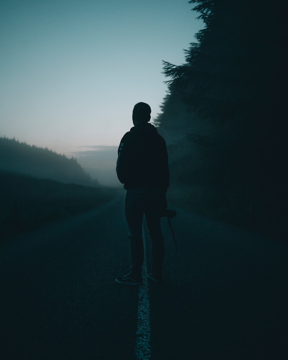 silhouette of man standing on road during daytime