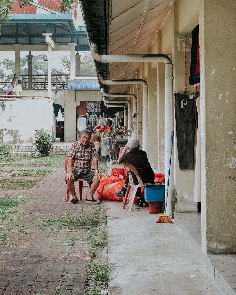 two men sitting on individual chair near building