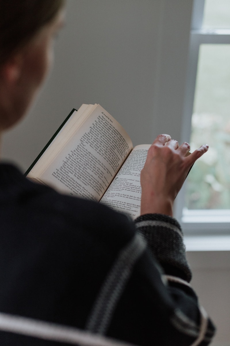 A woman reading a book in front of a window