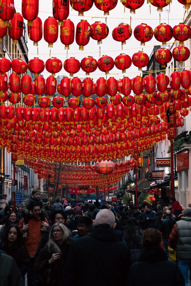 A group of people walking down a street under red lanterns