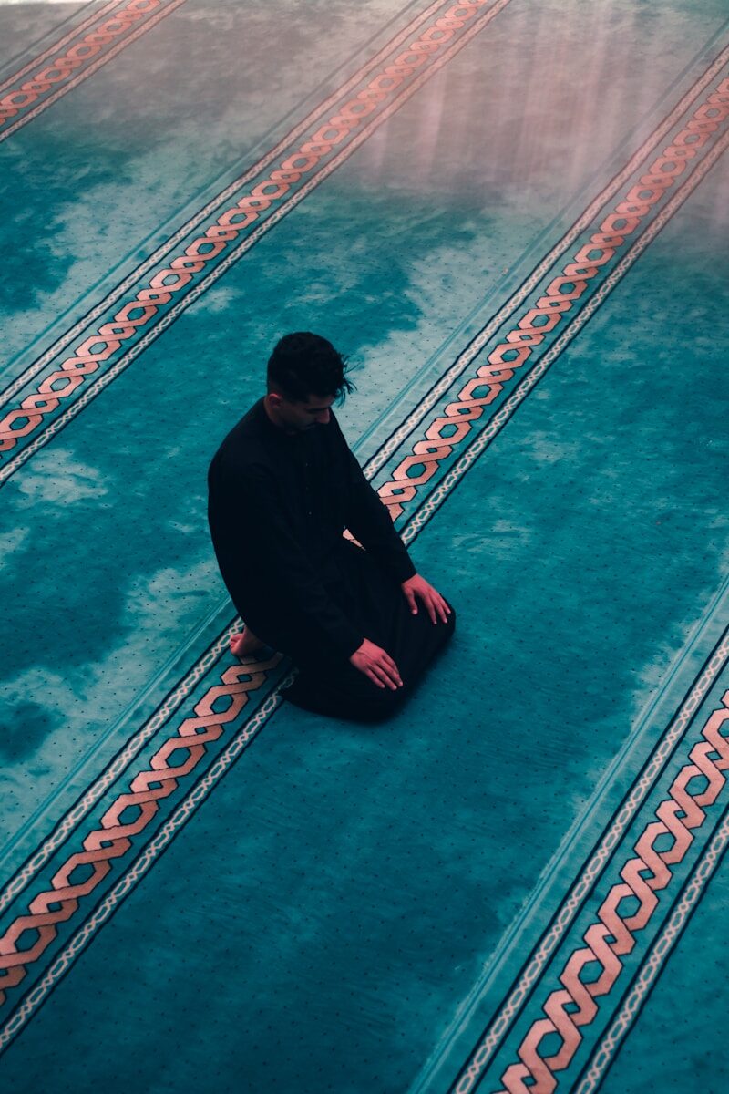 a man squatting on a sidewalk