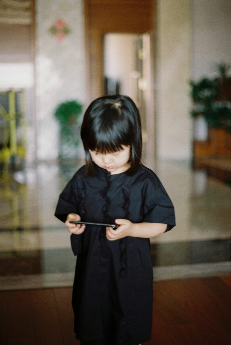 boy in black crew neck t-shirt standing on brown wooden floor