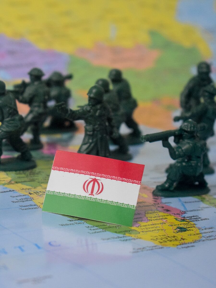Toy soldiers surround the flag of iran on a map.