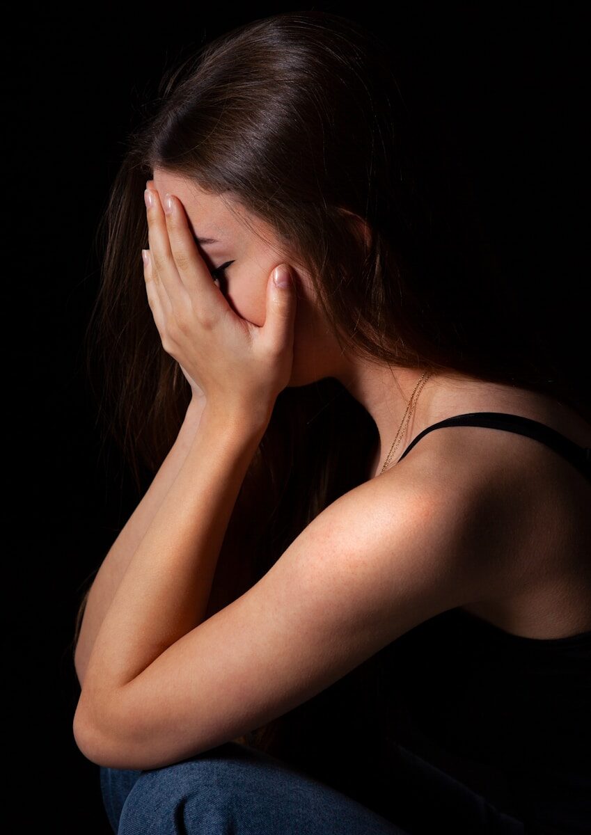a woman sitting down with her hands on her face