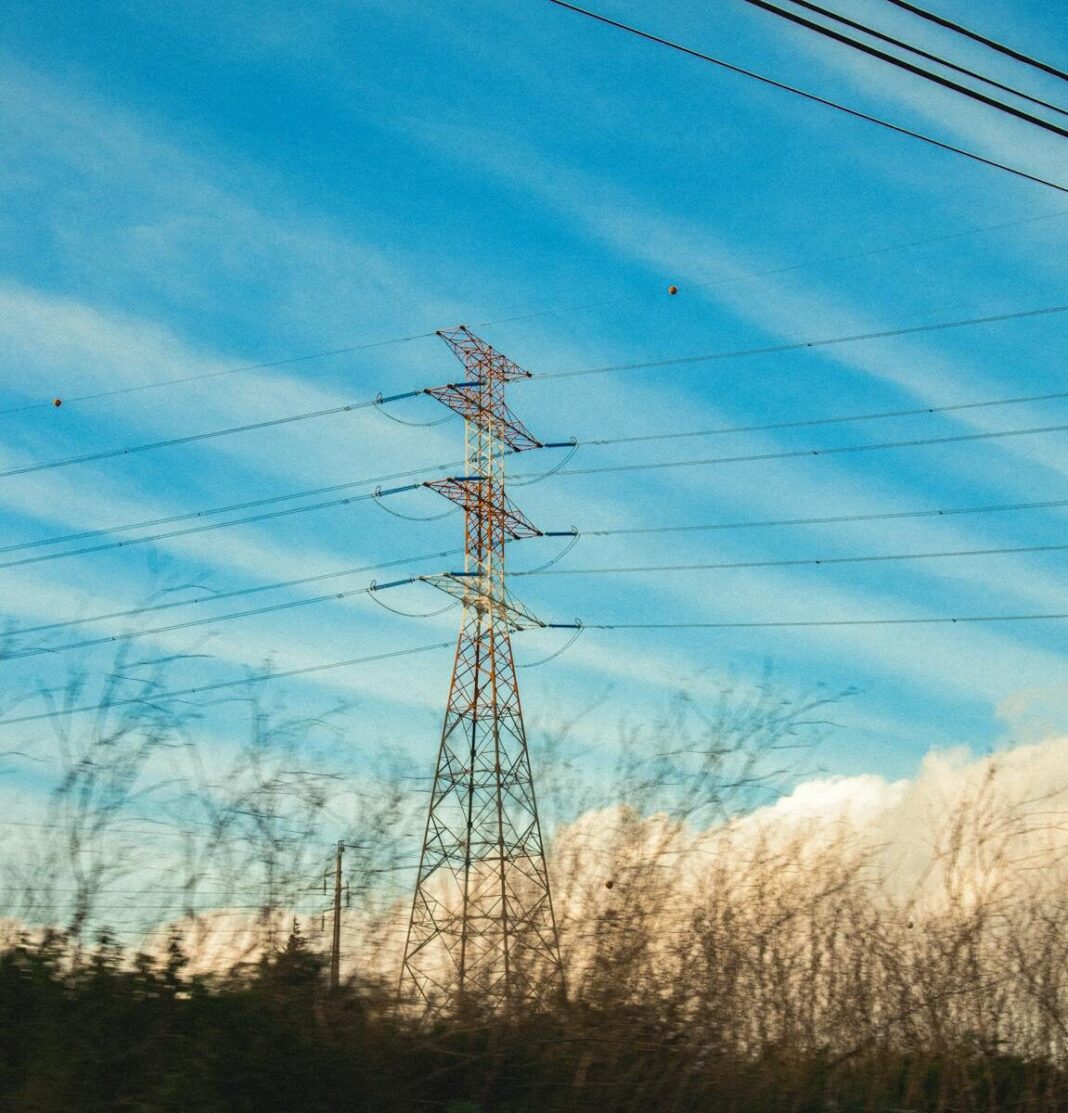 Powerful transmission tower framework under a vast blue sky, capturing the essence of electricity.
