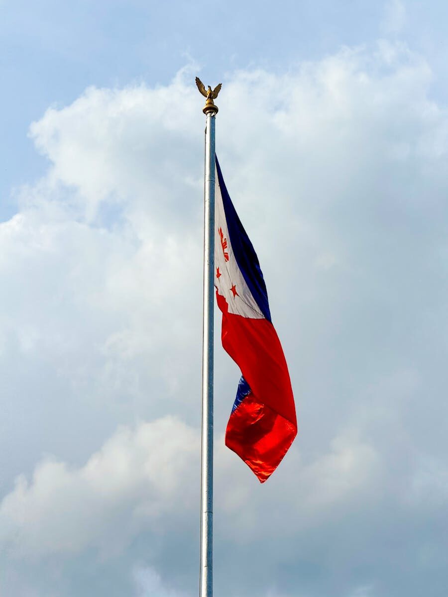 The Philippine flag flies proudly against a backdrop of clouds in Cebu City.