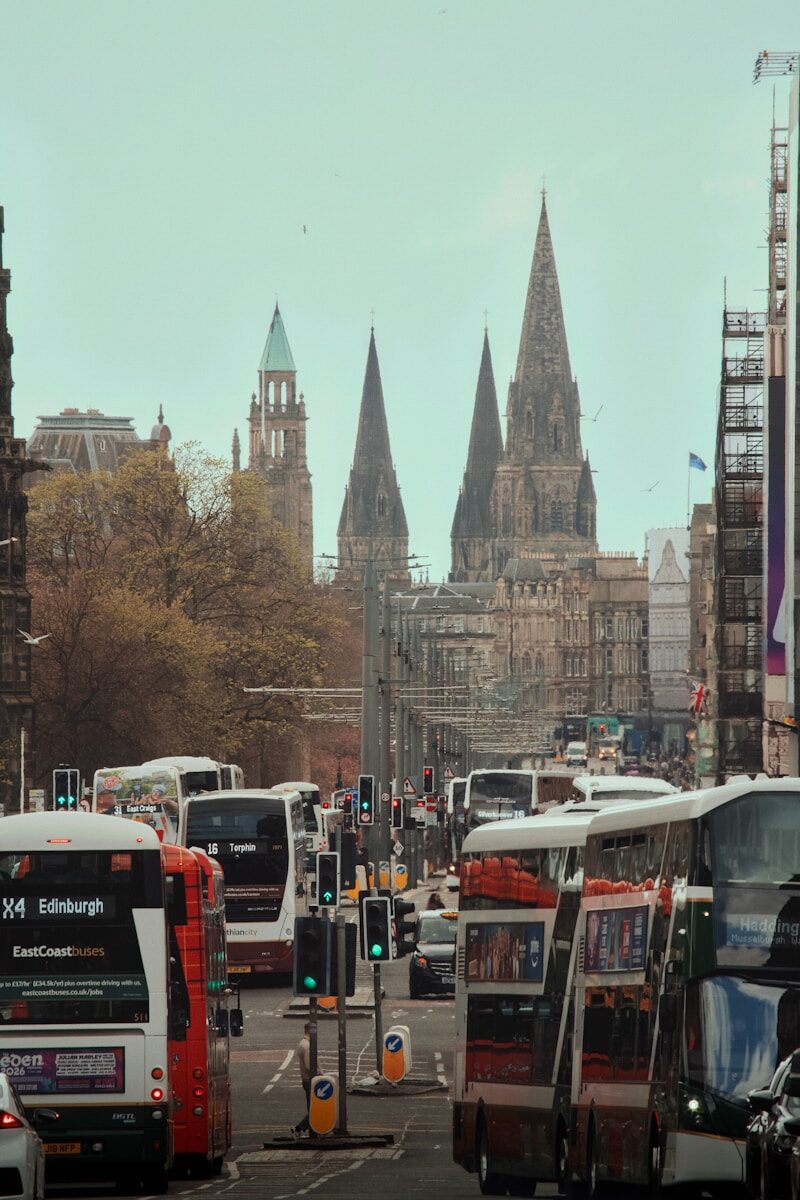 Buses and traffic on a city street with historic buildings.