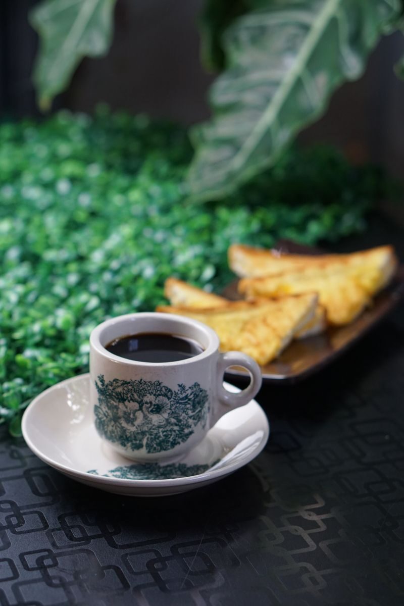 A warm cup of coffee with toast slices on a decorative table setting, perfect for breakfast.