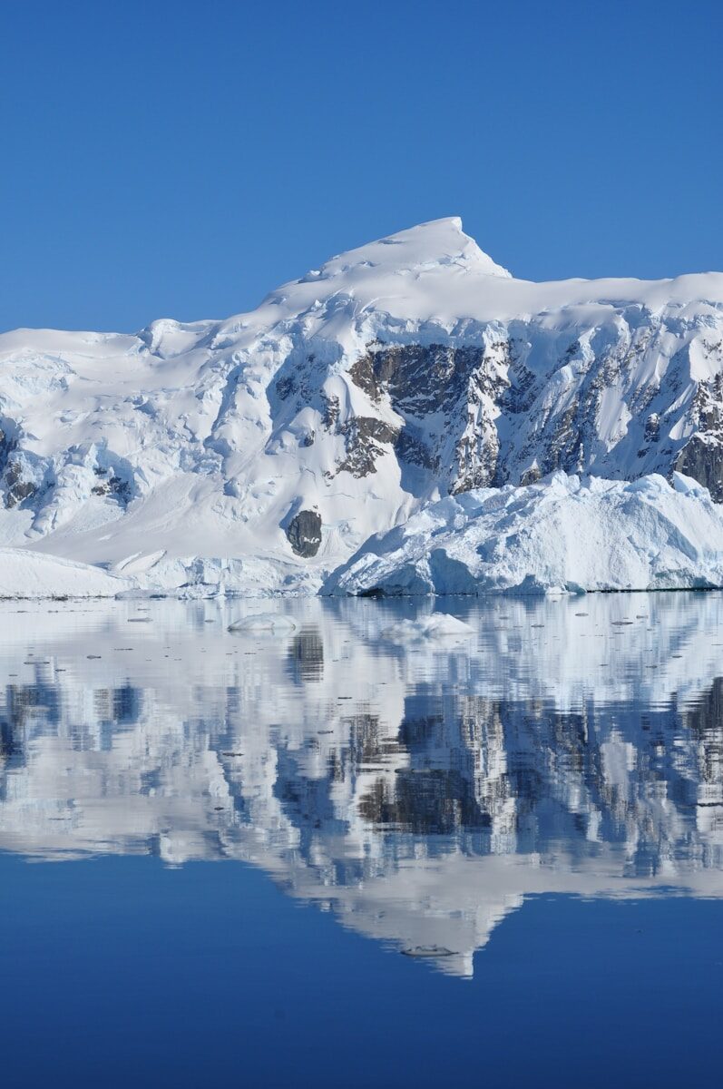 a snowy mountain with a body of water below