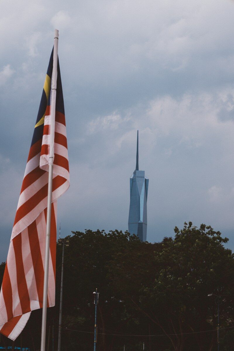 Malaysian flag flies before a modern skyscraper