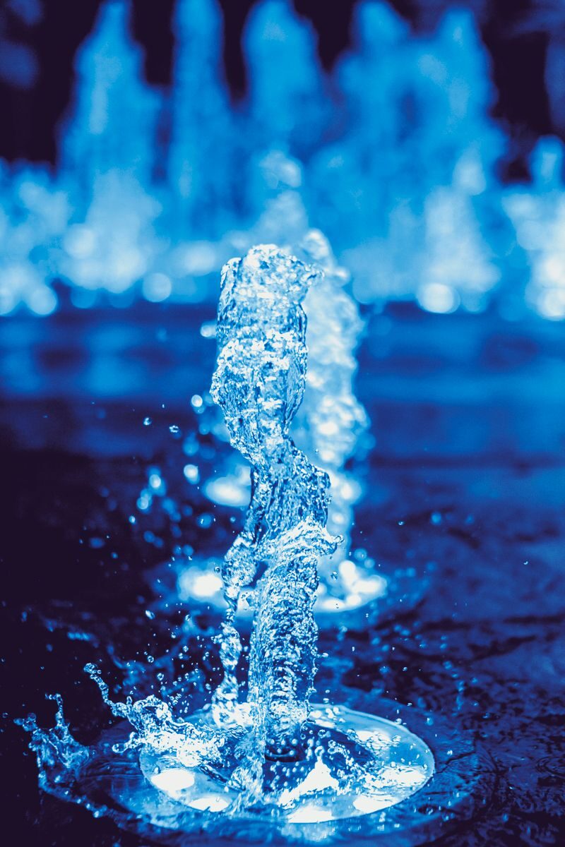 A dynamic close-up of a water fountain splash captured in vivid blue tones, showcasing motion and liquid beauty.