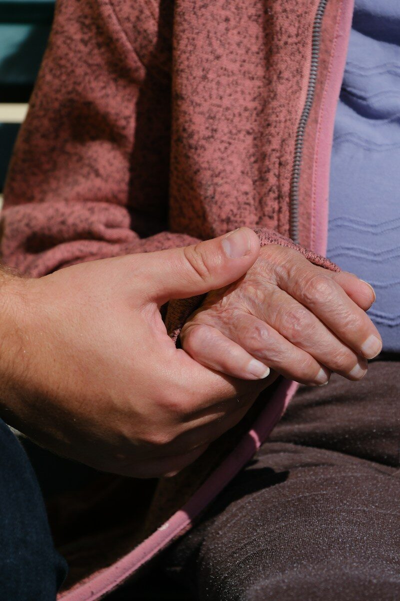 A person sitting on a bench holding their hands together